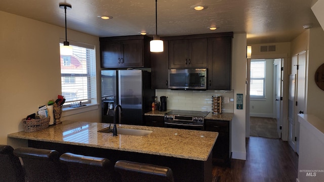 kitchen with light stone counters, sink, tasteful backsplash, dark hardwood / wood-style flooring, and stainless steel appliances