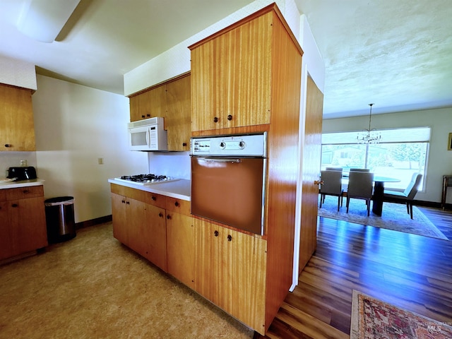 600 N 9th E, Mountain Home, ID 83647 - kitchen featuring white appliances, light wood-style floors, light countertops, a chandelier, and baseboards