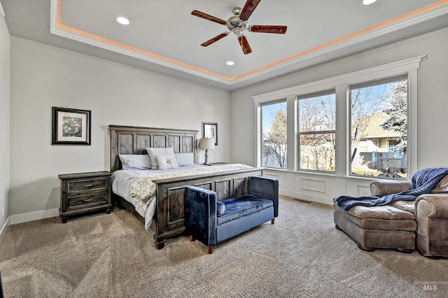 bedroom featuring light carpet, ceiling fan, ornamental molding, and a tray ceiling