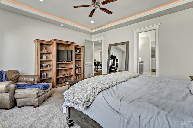 carpeted bedroom featuring ceiling fan, ensuite bathroom, ornamental molding, and a raised ceiling