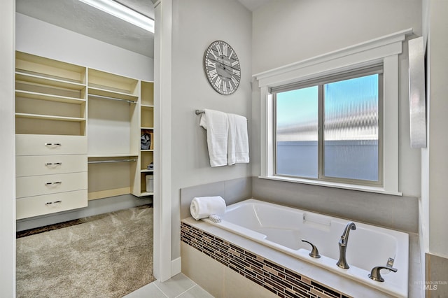 bathroom featuring a relaxing tiled tub, tile patterned flooring, and a healthy amount of sunlight