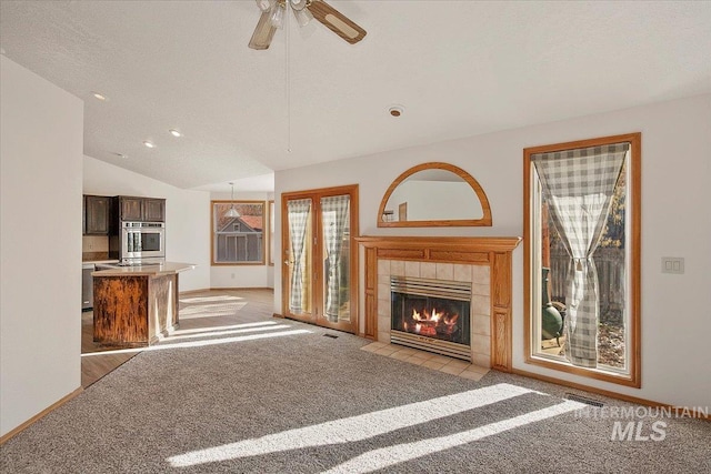 unfurnished living room with light carpet, a fireplace, baseboards, and lofted ceiling