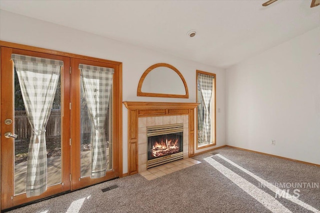 unfurnished living room with carpet, visible vents, baseboards, and a tile fireplace