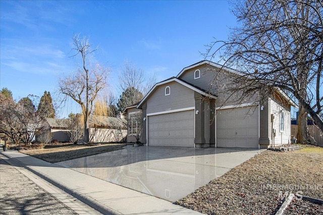 view of front of home with concrete driveway, fence, and an attached garage