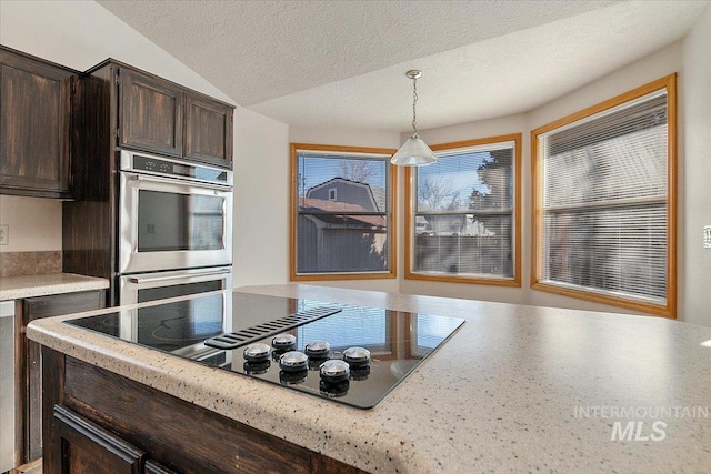 kitchen featuring dark brown cabinetry, black electric cooktop, light countertops, double oven, and pendant lighting