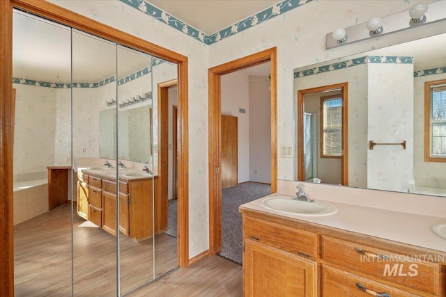 full bathroom featuring wallpapered walls, a washtub, wood finished floors, and vanity