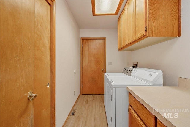 laundry room with visible vents, light wood finished floors, independent washer and dryer, and cabinet space