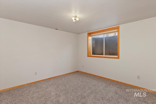 unfurnished room with carpet flooring, visible vents, and baseboards