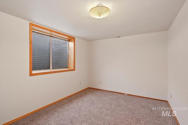 unfurnished room featuring carpet floors, baseboards, visible vents, and a textured ceiling