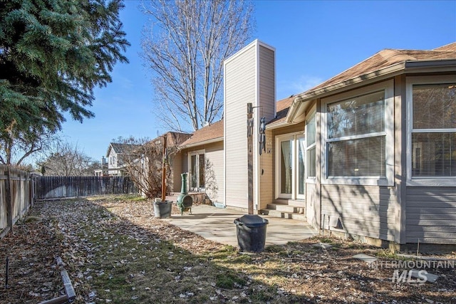 back of property with entry steps, a fenced backyard, a patio, and a chimney