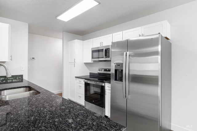 1590 Saddler St, Twin Falls, ID 83301 - kitchen featuring appliances with stainless steel finishes, a sink, dark stone counters, and white cabinetry