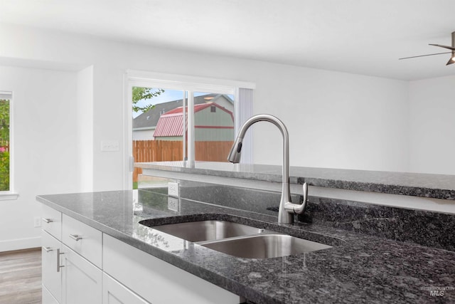 1590 Saddler St, Twin Falls, ID 83301 - kitchen view of a sink, white cabinetry, dark stone countertops, light wood-style flooring, and a ceiling fan