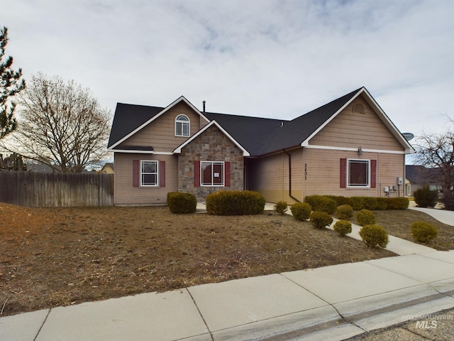 view of front of property featuring stone siding and fence