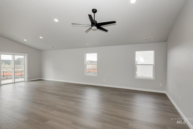 empty room featuring recessed lighting, wood finished floors, visible vents, baseboards, and vaulted ceiling