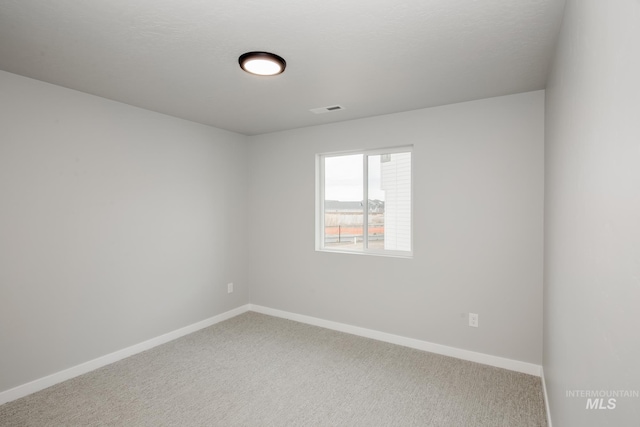 carpeted spare room featuring visible vents and baseboards