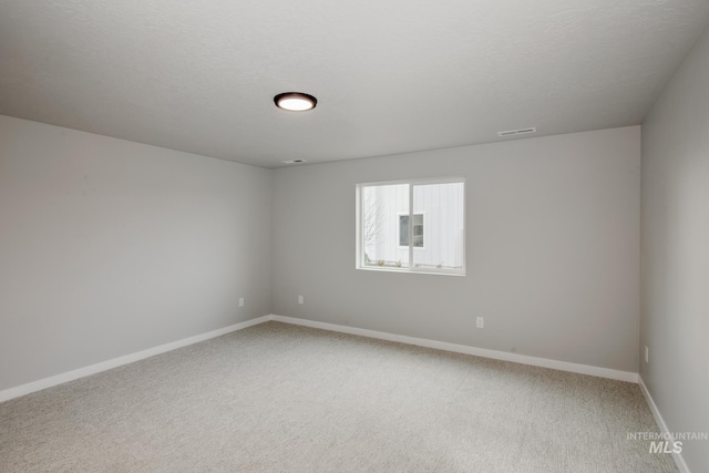 empty room featuring baseboards, a textured ceiling, visible vents, and light colored carpet