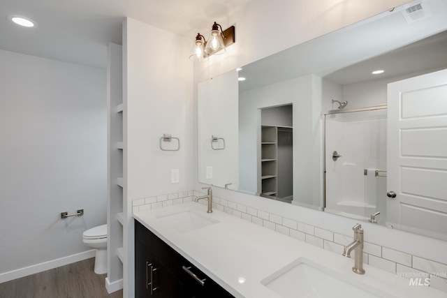 full bath featuring a shower, wood finished floors, a sink, and toilet