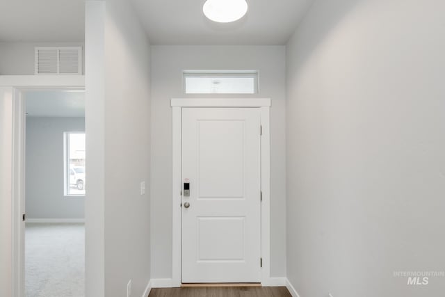 doorway with wood finished floors, visible vents, and baseboards