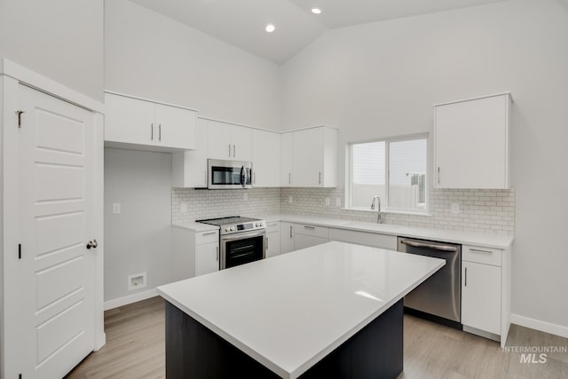 kitchen featuring high vaulted ceiling, stainless steel appliances, light countertops, white cabinetry, and a sink