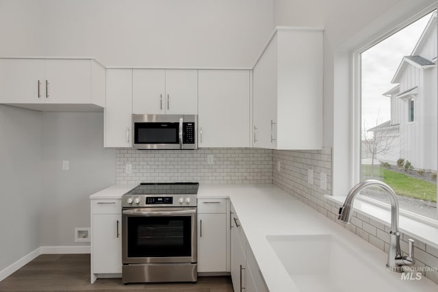 kitchen featuring appliances with stainless steel finishes, light countertops, white cabinetry, and a sink