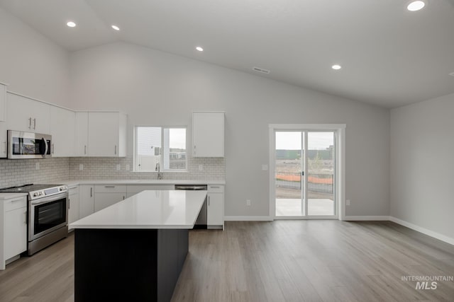 kitchen with a healthy amount of sunlight, a kitchen island, stainless steel appliances, and light countertops