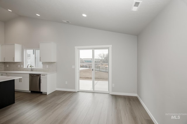 kitchen featuring a healthy amount of sunlight, backsplash, light countertops, and stainless steel dishwasher