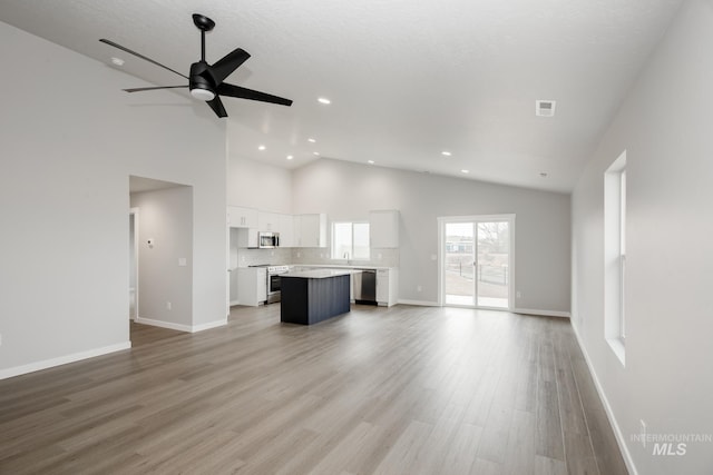 unfurnished living room featuring ceiling fan, a sink, visible vents, baseboards, and light wood finished floors