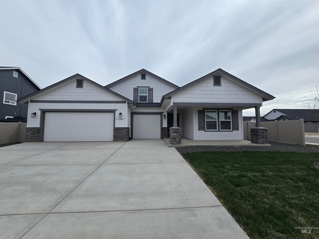 11581 W Trooper St, Nampa, ID 83651 - view of front of home with fence, a garage, concrete driveway, stone siding, and a front lawn