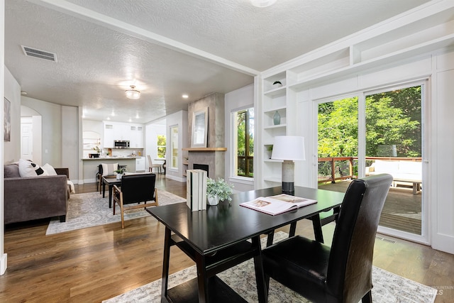 2383 E Lenox Ct, Eagle, ID 83616 - dining area featuring a textured ceiling, wood finished floors, a large fireplace, built in shelves, and baseboards