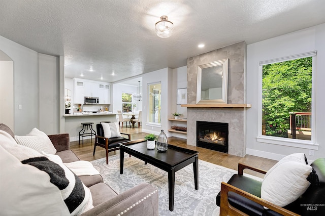 2383 E Lenox Ct, Eagle, ID 83616 - living area featuring plenty of natural light, a textured ceiling, a tile fireplace, light wood-style floors, and recessed lighting