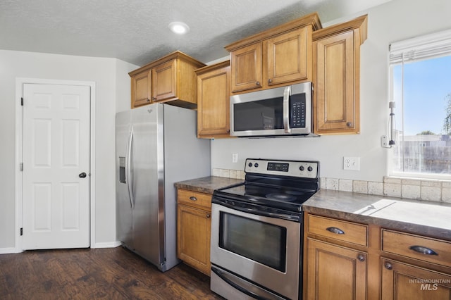 841 Shire St, Middleton, ID 83644 - kitchen with stainless steel appliances, brown cabinets, dark wood-style flooring, dark countertops, and a textured ceiling