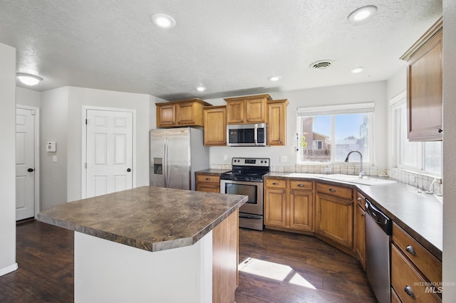 841 Shire St, Middleton, ID 83644 - kitchen featuring appliances with stainless steel finishes, a sink, dark wood finished floors, brown cabinets, and a kitchen island