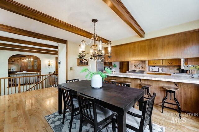 928 N Argyll Dr, Boise, ID 83702 - dining area with beam ceiling, a chandelier, arched walkways, and light wood-style flooring