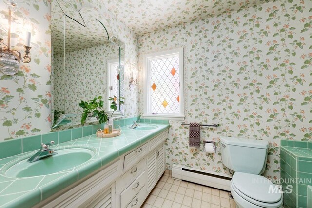 928 N Argyll Dr, Boise, ID 83702 - bathroom with a baseboard radiator, wallpapered walls, double vanity, toilet, and tile patterned floors
