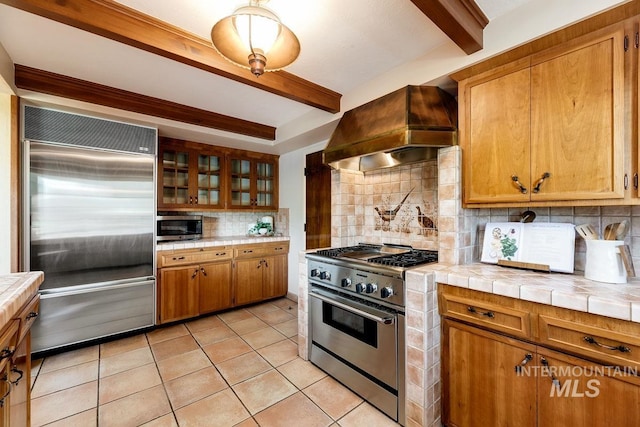 928 N Argyll Dr, Boise, ID 83702 - kitchen with high end appliances, custom exhaust hood, beam ceiling, tile countertops, and brown cabinets