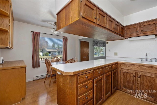 371 Dubois, Twin Falls, ID 83301 - kitchen with brown cabinets, light wood-style floors, a ceiling fan, a peninsula, and a baseboard radiator