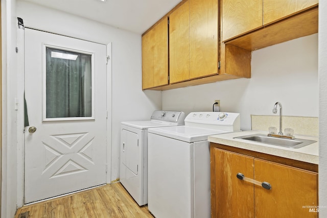 washroom featuring sink, washer and clothes dryer, light hardwood / wood-style floors, and cabinets