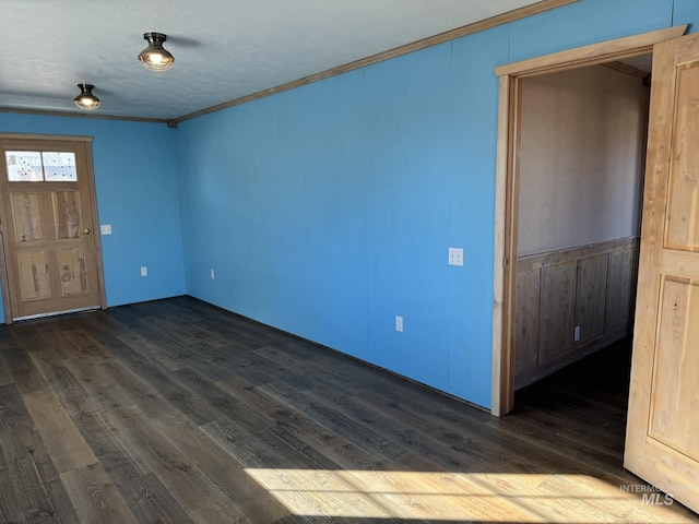 empty room featuring dark wood-style floors, a textured ceiling, and crown molding