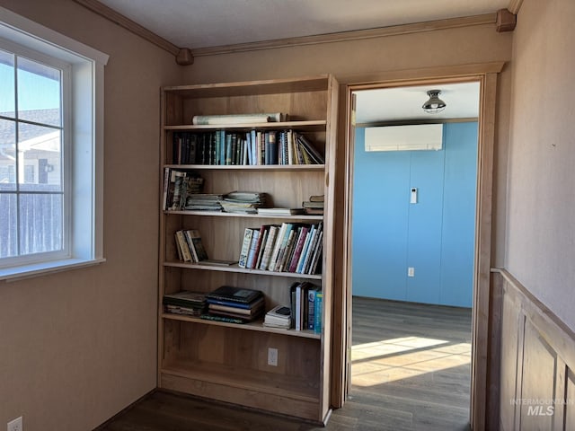 hallway with ornamental molding, wood finished floors, and a wall mounted AC