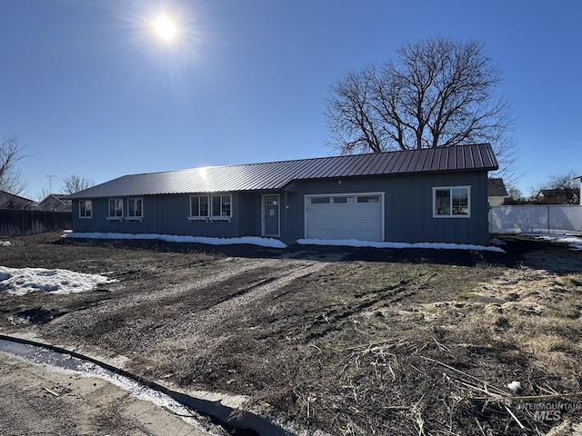 ranch-style house with metal roof, an attached garage, fence, and driveway