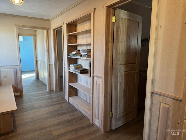 hallway with ornamental molding, dark wood-type flooring, and built in features