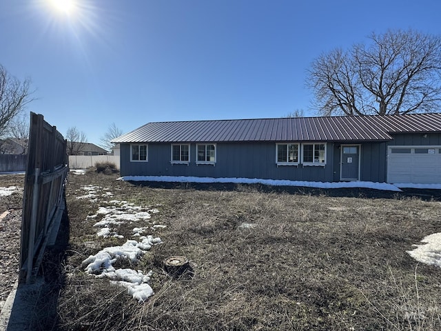 view of front of house with a garage, metal roof, and fence