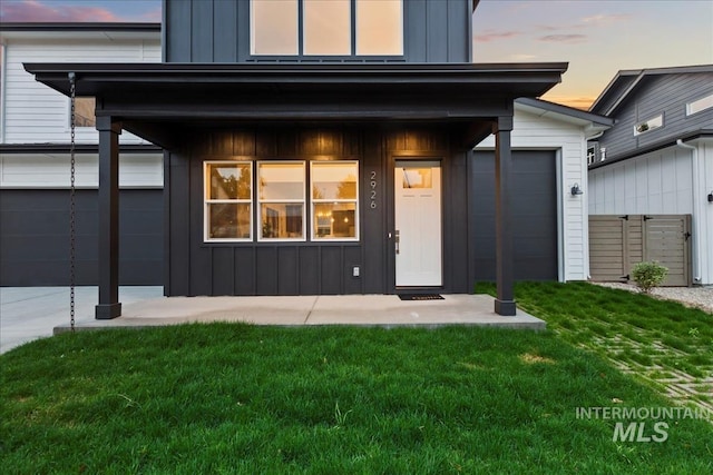 exterior entry at dusk featuring a yard and a garage