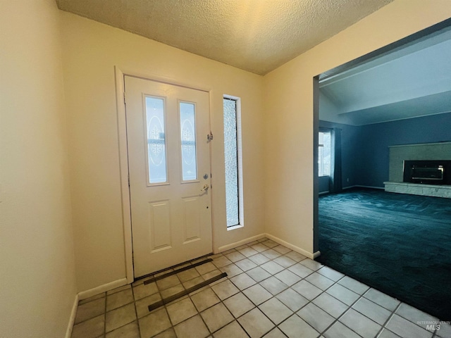 tiled foyer entrance with a fireplace and a textured ceiling