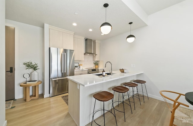 4340 E Haystack St Unit 205, Boise, ID 83716 - kitchen with stainless steel appliances, wall chimney range hood, a kitchen bar, a peninsula, and light wood finished floors