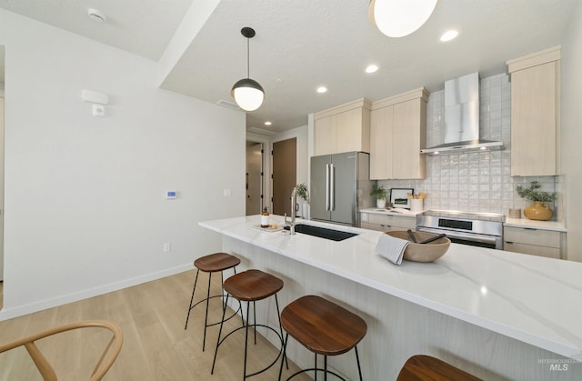 4340 E Haystack St Unit 205, Boise, ID 83716 - kitchen with wall chimney exhaust hood, stainless steel appliances, a kitchen bar, light wood-style flooring, and backsplash