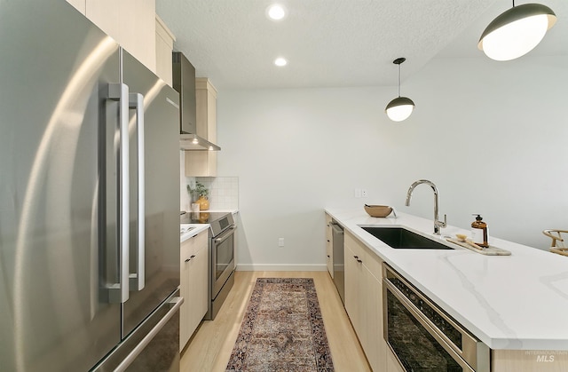 4340 E Haystack St Unit 205, Boise, ID 83716 - kitchen featuring stainless steel appliances, wall chimney range hood, light wood-type flooring, a peninsula, and a textured ceiling