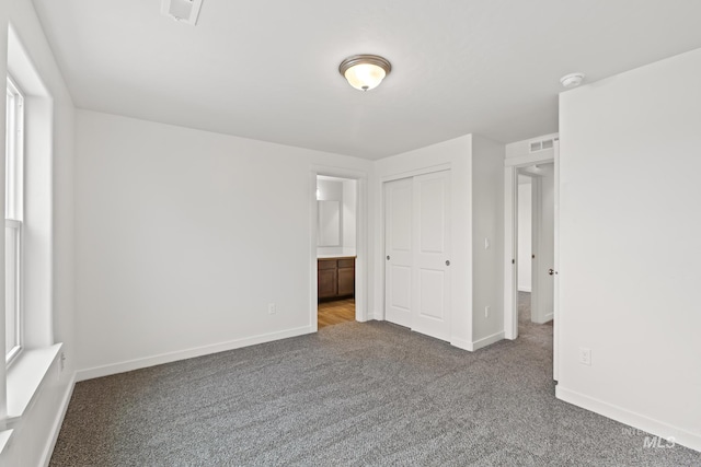 unfurnished bedroom featuring carpet, a closet, and ensuite bath