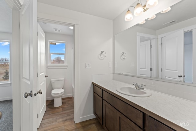 bathroom featuring a chandelier, hardwood / wood-style floors, vanity, and toilet