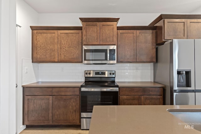 kitchen with stainless steel appliances, tasteful backsplash, and light hardwood / wood-style floors